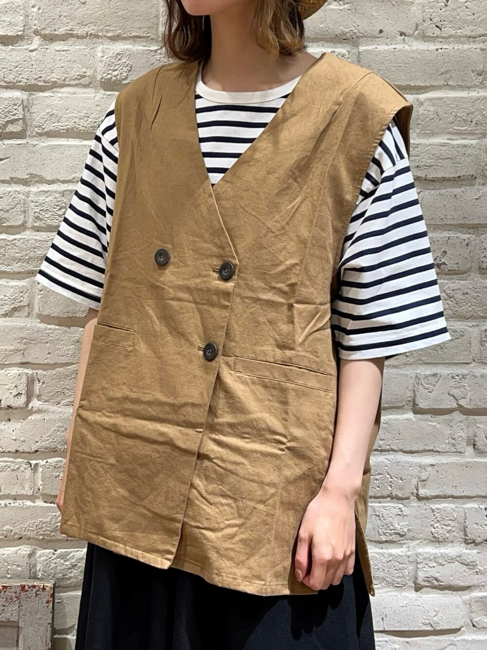 ホワイト系のTシャツ/カットソー、ベージュ系のベスト、ブラック系のハンドバッグを着用したレディースの春コーディネートの2枚目の写真