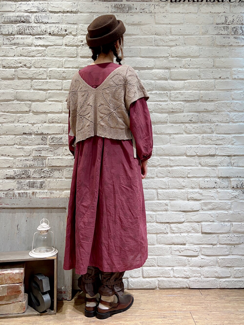 ベージュ系のベスト、レッド系のワンピース、グレー系のその他パンツを着用したレディースの秋コーディネートの4枚目の写真