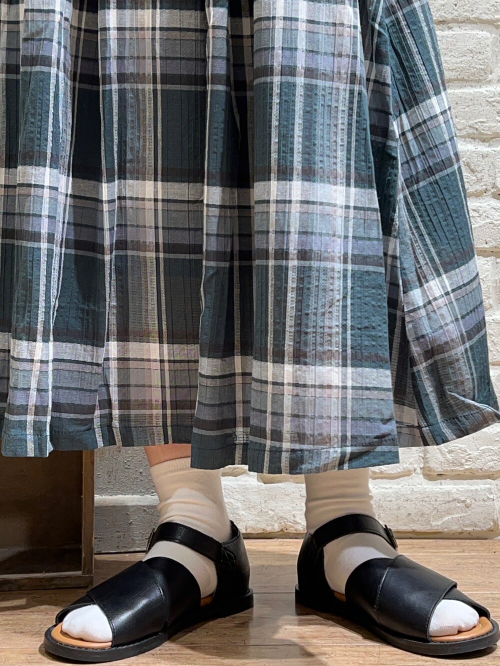 ベージュ系のTシャツ/カットソー、ブラック系のワンピース、グリーン系のスカートを着用したレディースの春コーディネートの5枚目の写真