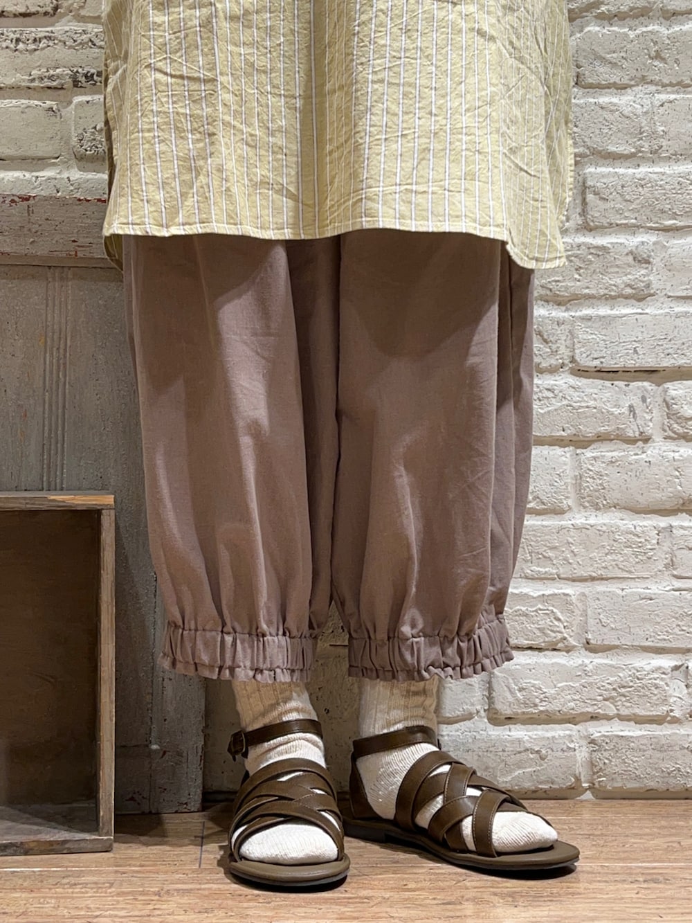 ホワイト系のタンクトップ、ブラウン系のベスト、イエロー系のチュニックを着用したレディースの夏コーディネートの5枚目の写真