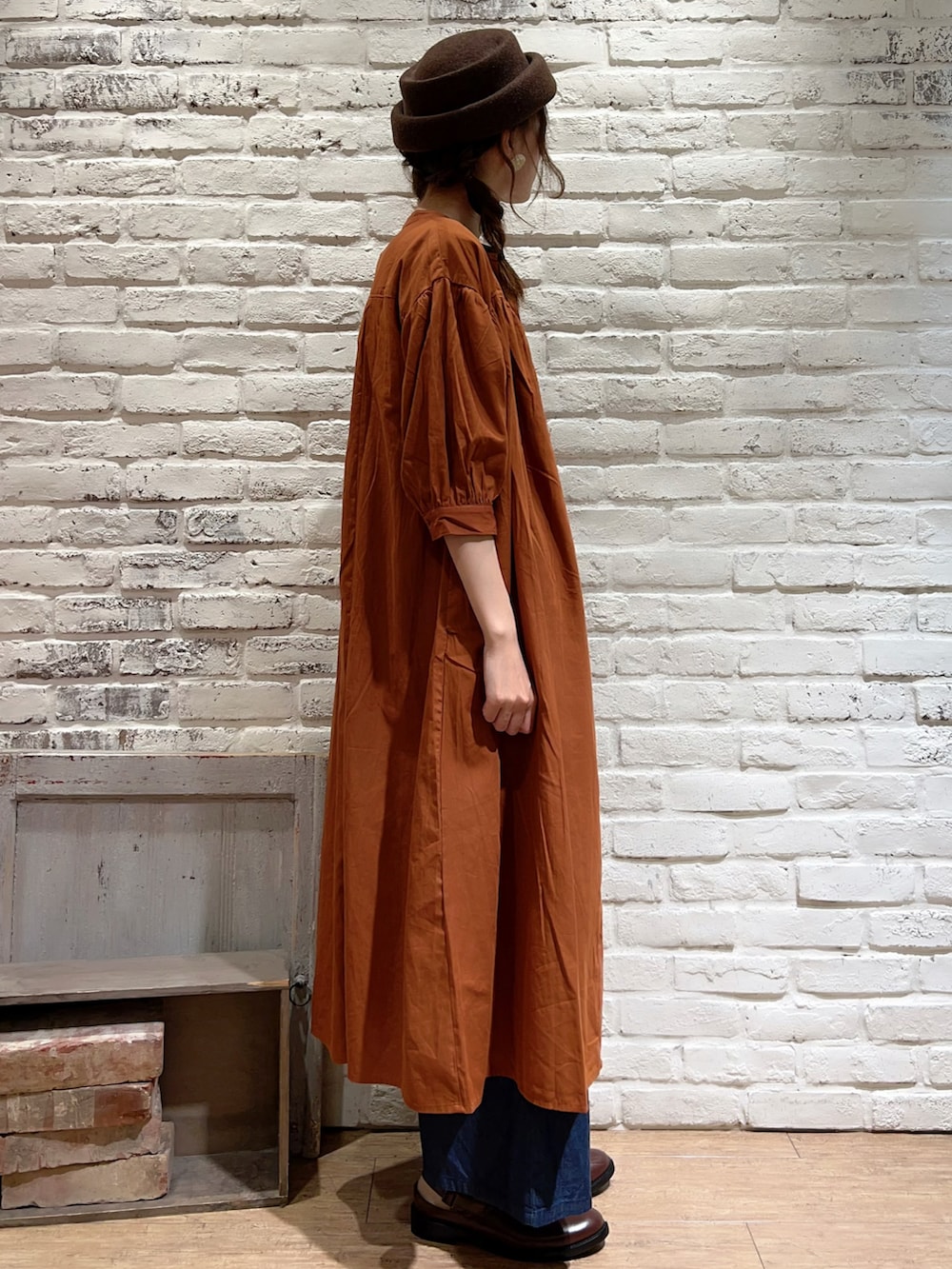 ベージュ系のTシャツ/カットソー、オレンジ系のワンピース、ブルー系のデニムパンツを着用したレディースの夏コーディネートの3枚目の写真