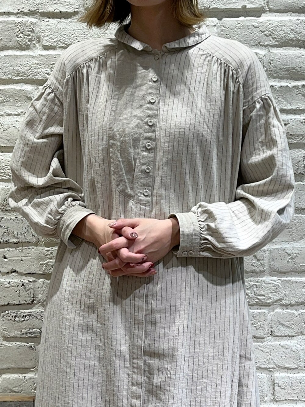 ブラウン系のカーディガン/ボレロ、ベージュ系のワンピース、ブラック系のスカートを着用したレディースの秋コーディネートの3枚目の写真