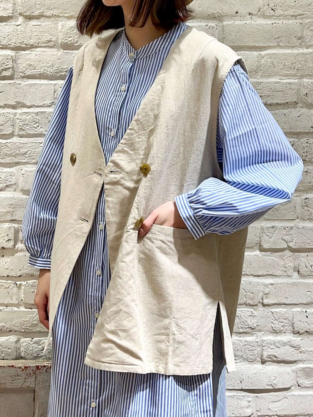 ホワイト系のベスト、ブラック系のハンドバッグ、ブルー系のシャツワンピースを着用したレディースの春コーディネートの2枚目の写真