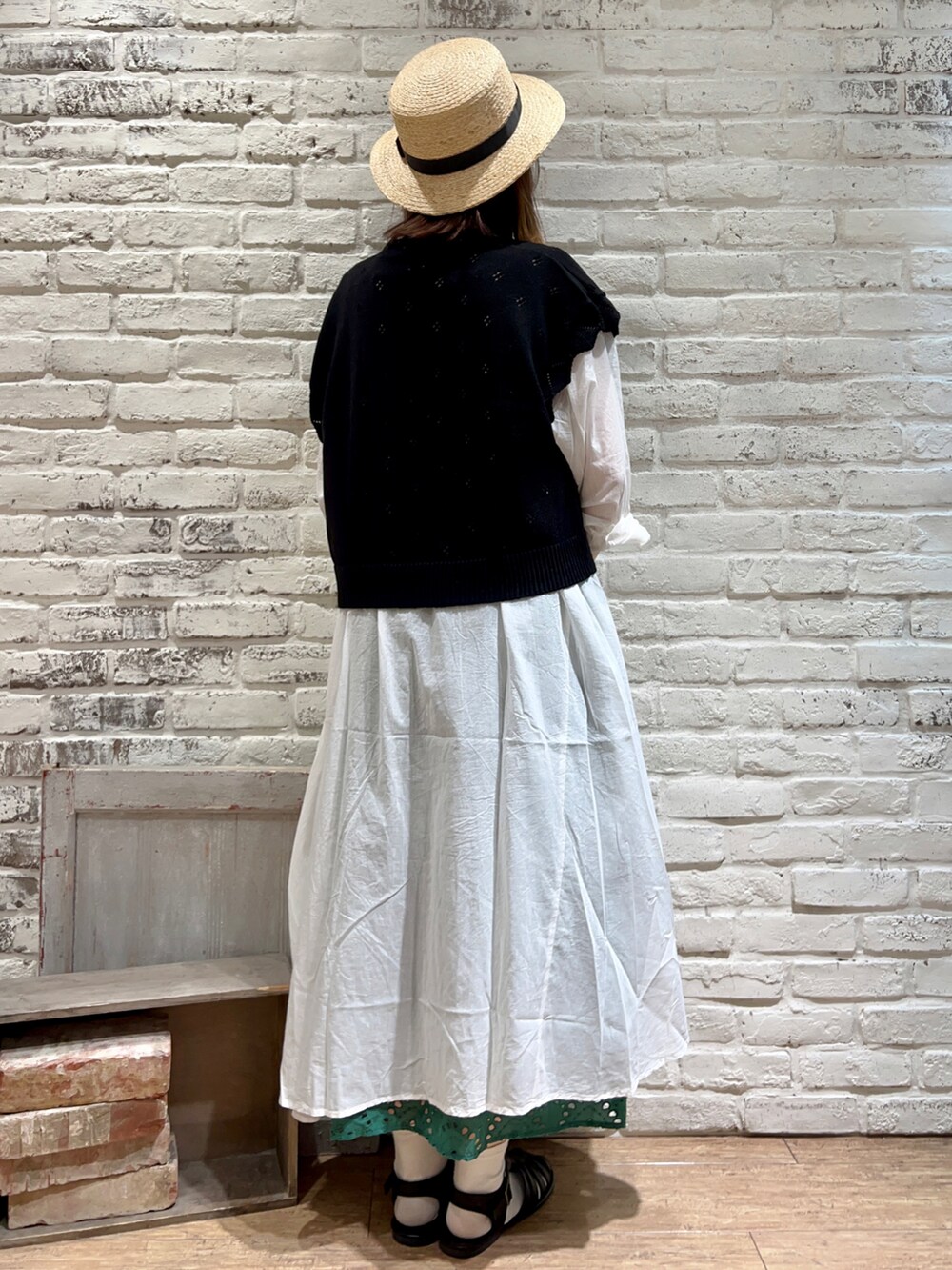 ホワイト系のタンクトップ、ブラック系のベスト、ホワイト系のワンピースを着用したレディースの春コーディネートの3枚目の写真