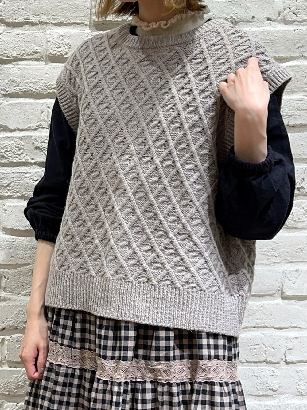 ホワイト系のニット/セーター、ベージュ系のベスト、ブラック系のシャツ/ブラウスを着用したレディースの秋コーディネートの2枚目の写真