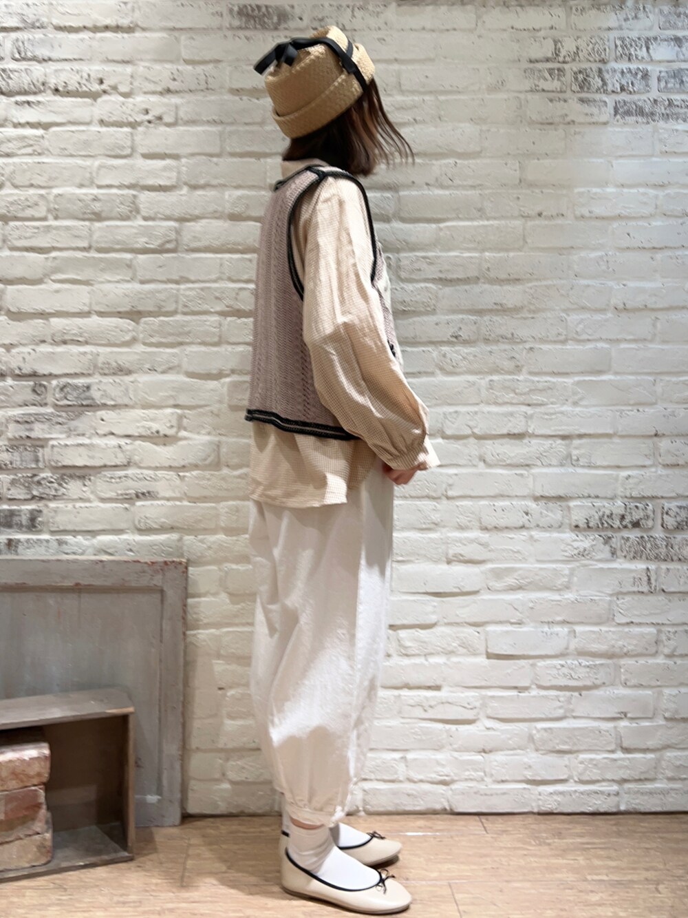 ベージュ系のシャツ/ブラウス、ベージュ系のベスト、ホワイト系のハンドバッグを着用したレディースの春コーディネートの3枚目の写真