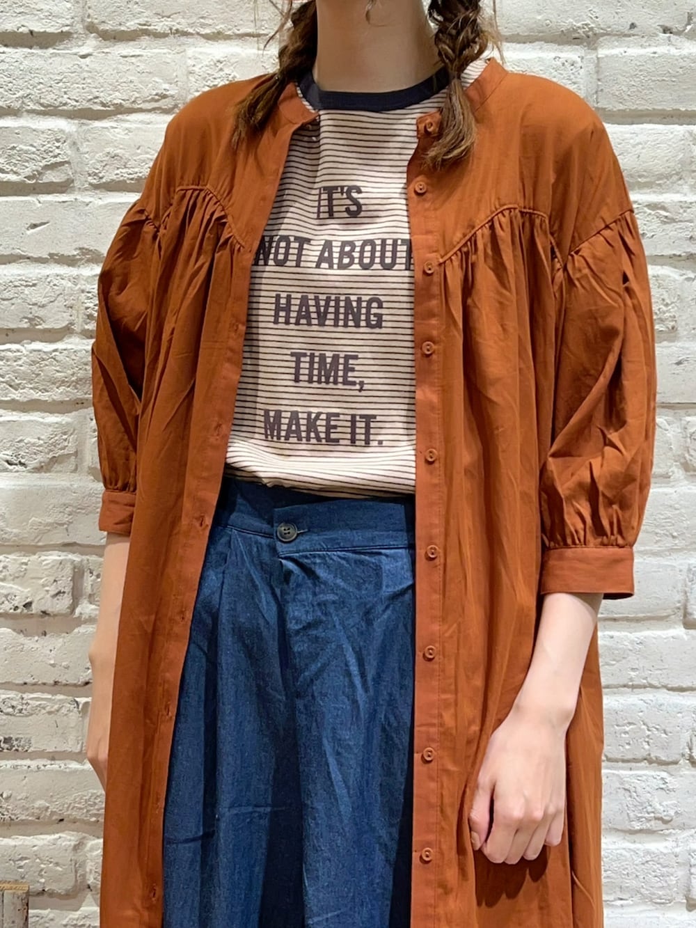 ベージュ系のTシャツ/カットソー、オレンジ系のワンピース、ブルー系のデニムパンツを着用したレディースの夏コーディネートの2枚目の写真