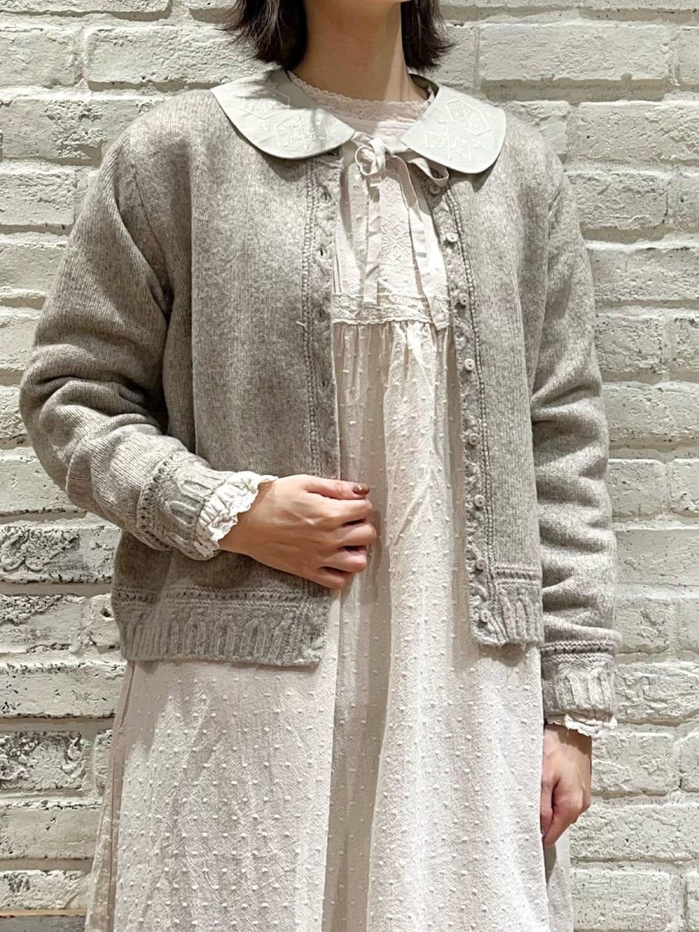 ベージュ系のカーディガン/ボレロ、ホワイト系のワンピース、ブラウン系のハンドバッグを着用したレディースの冬コーディネートの2枚目の写真