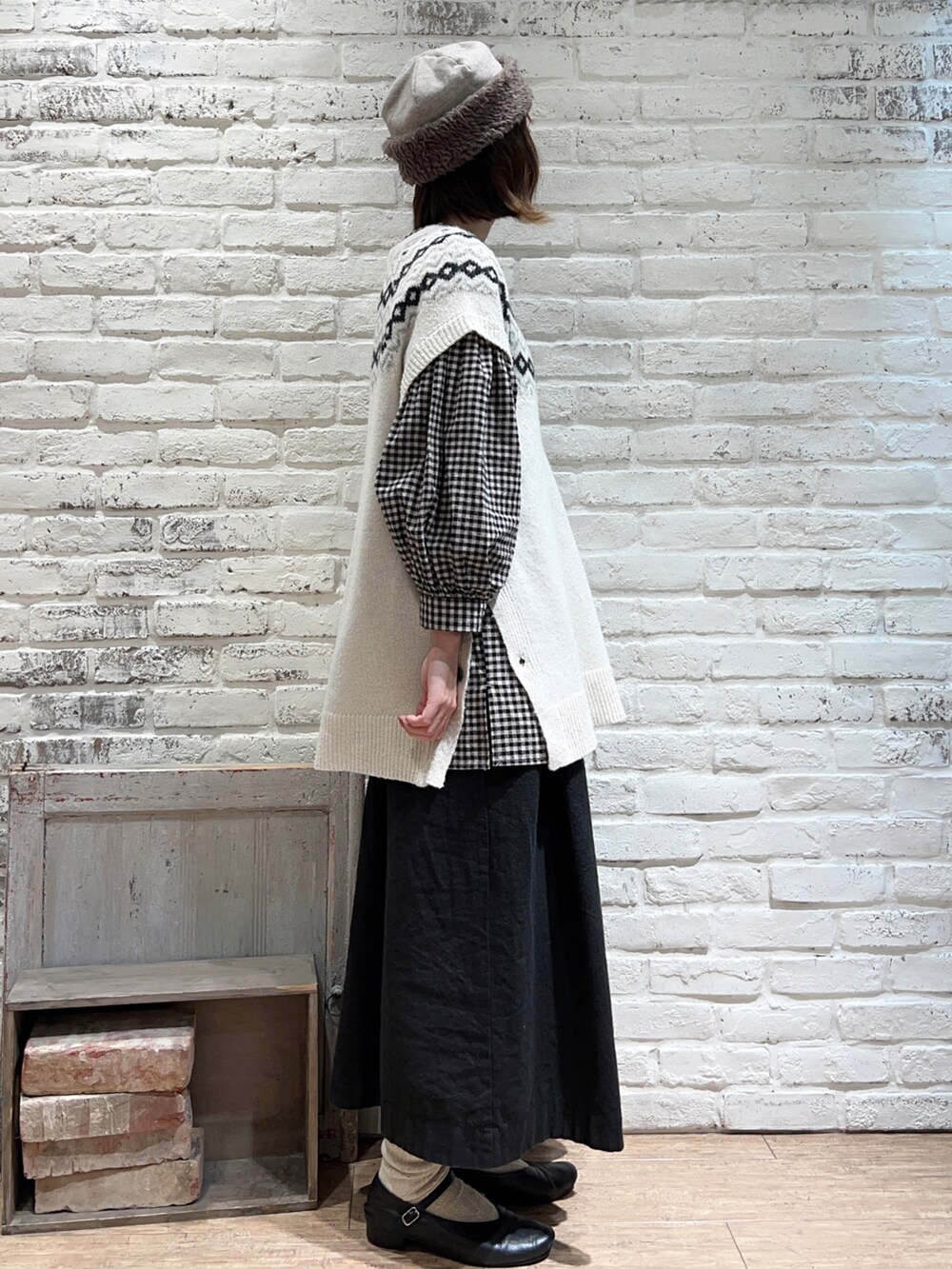 ホワイト系のベスト、ブラック系のチュニック、ブラック系のスカートを着用したレディースの冬コーディネートの3枚目の写真