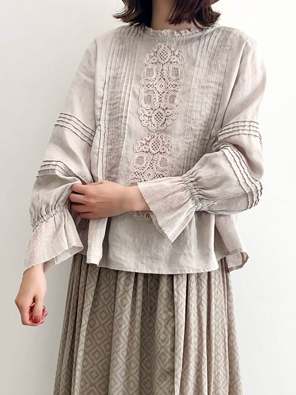 グレー系のスカート、ホワイト系のパンプス、ベージュ系のシャツ/ブラウスを着用したレディースの春コーディネートの2枚目の写真