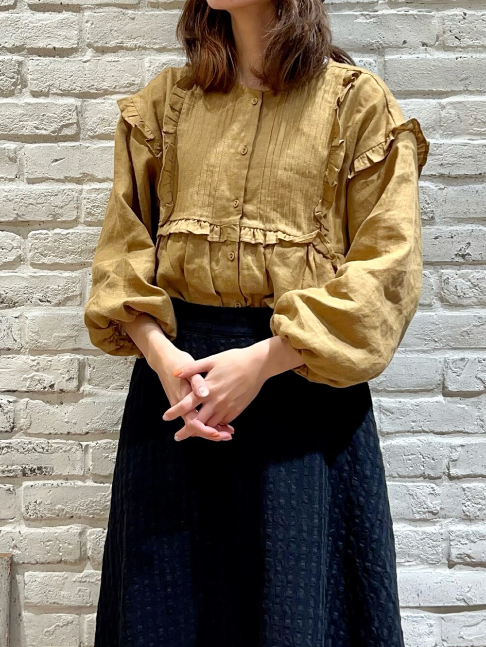 イエロー系のチュニック、ブラック系のスカート、ブラック系のハットを着用したレディースの秋コーディネートの2枚目の写真