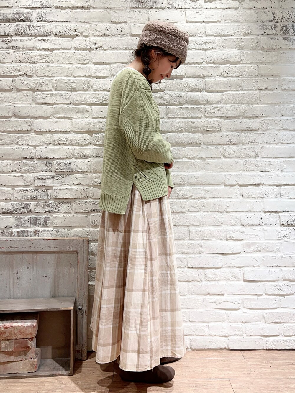 グリーン系のニット/セーター、ベージュ系のスカート、ブラウン系のブーツを着用したレディースの冬コーディネートの3枚目の写真