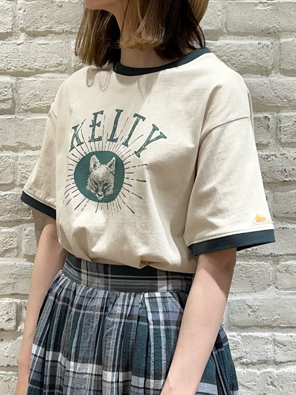 ベージュ系のTシャツ/カットソー、ブラック系のワンピース、グリーン系のスカートを着用したレディースの春コーディネートの2枚目の写真