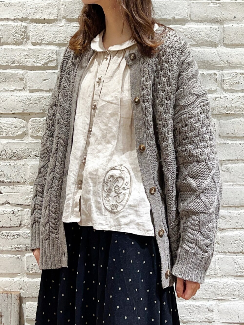 ベージュ系のシャツ/ブラウス、ブラウン系のカーディガン/ボレロ、ブラック系のスカートを着用したレディースの冬コーディネートの2枚目の写真