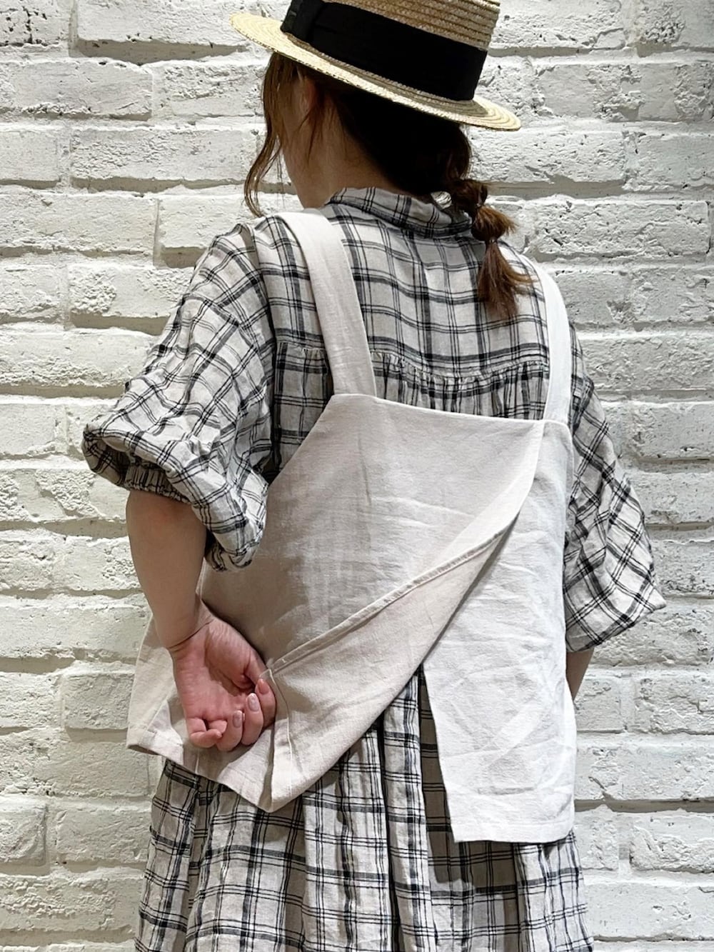 ベージュ系のベスト、ホワイト系のワンピース、ブラック系のスカートを着用したレディースの夏コーディネートの5枚目の写真