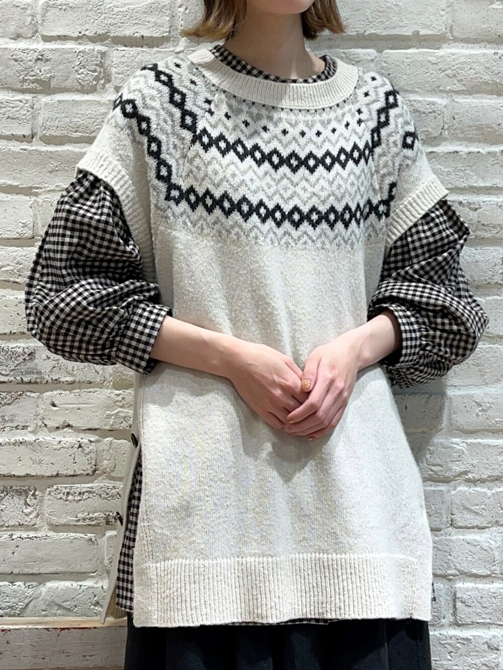 ホワイト系のベスト、ブラック系のチュニック、ブラック系のスカートを着用したレディースの冬コーディネートの2枚目の写真