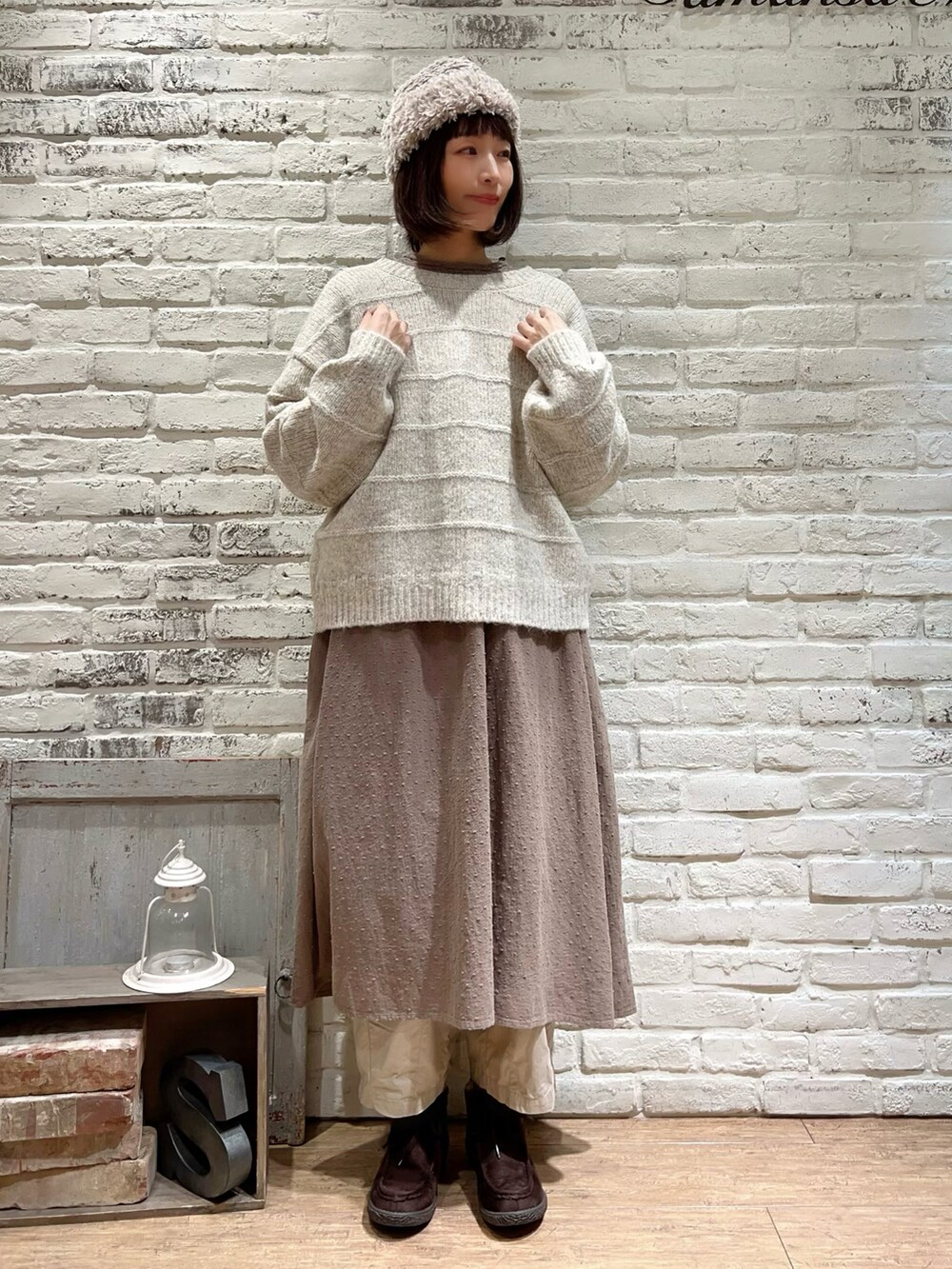 ホワイト系のカーディガン/ボレロ、ブラウン系のワンピース、ベージュ系のカーゴパンツを着用したレディースの冬コーディネートの4枚目の写真