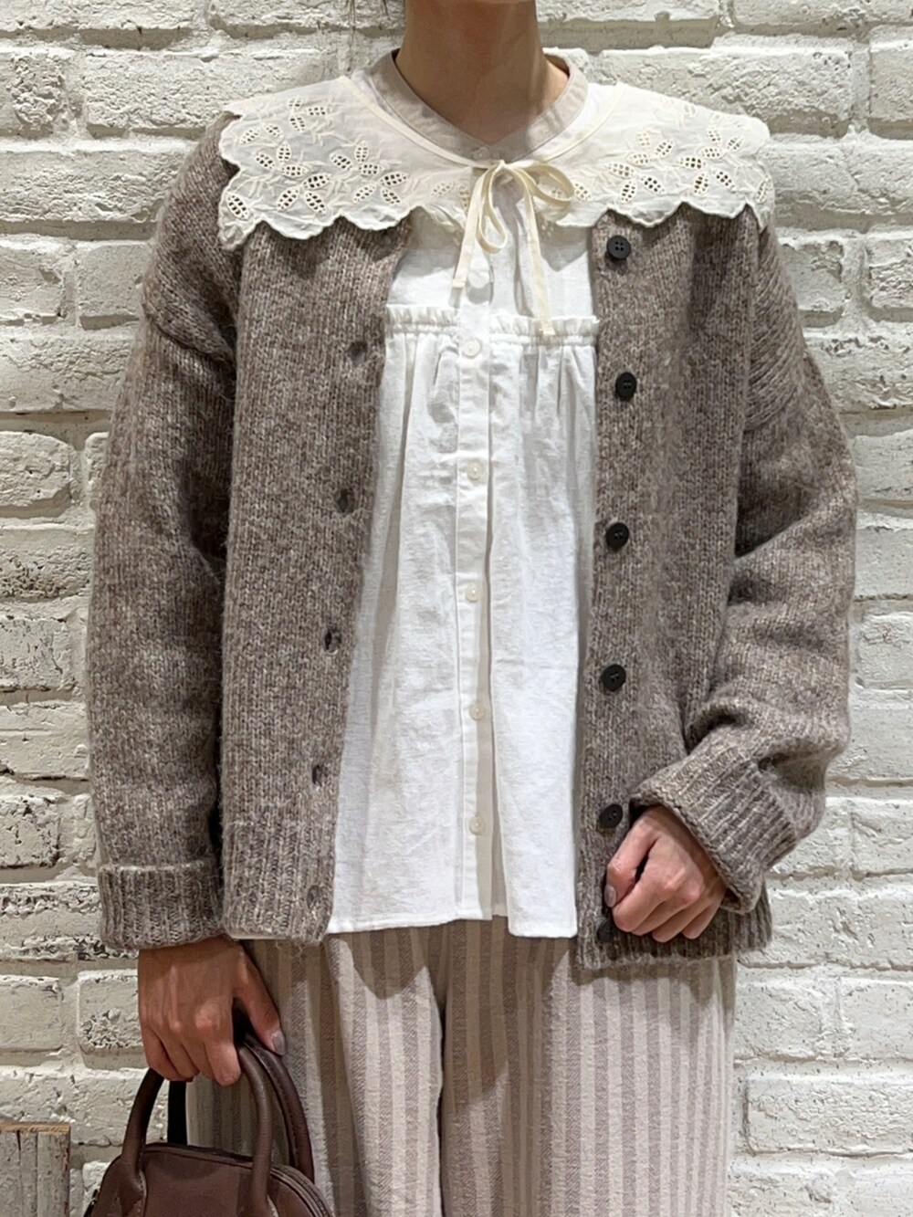 ブラウン系のカーディガン/ボレロ、ホワイト系のシャツ/ブラウス、ブラウン系のショルダーバッグを着用したレディースの冬コーディネートの2枚目の写真