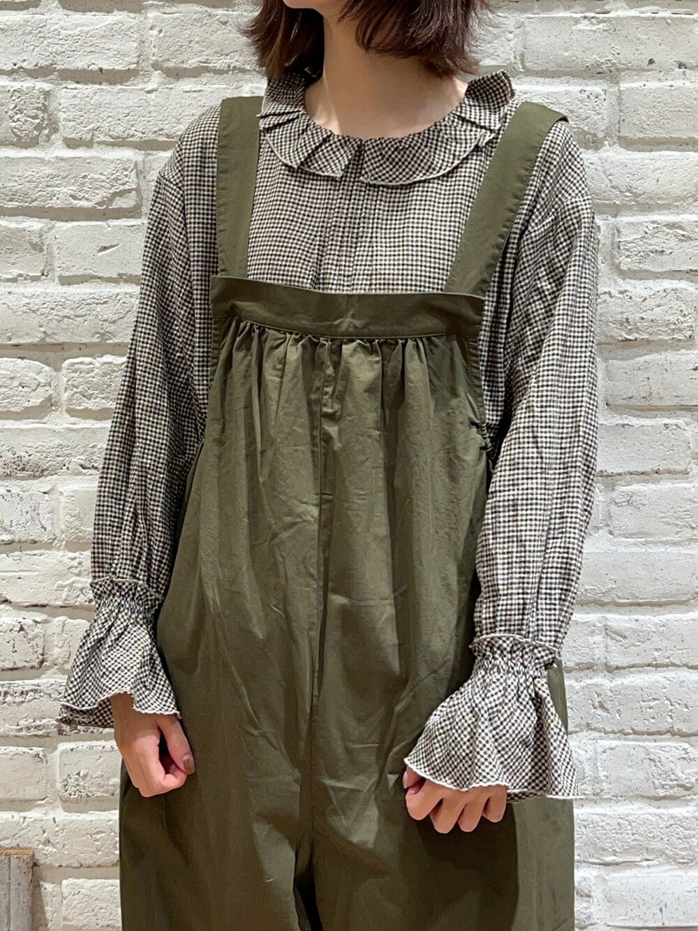 ブラウン系のシャツ/ブラウス、ホワイト系のカーディガン/ボレロ、グリーン系のサロペット/オーバーオールを着用したレディースの冬コーディネートの3枚目の写真