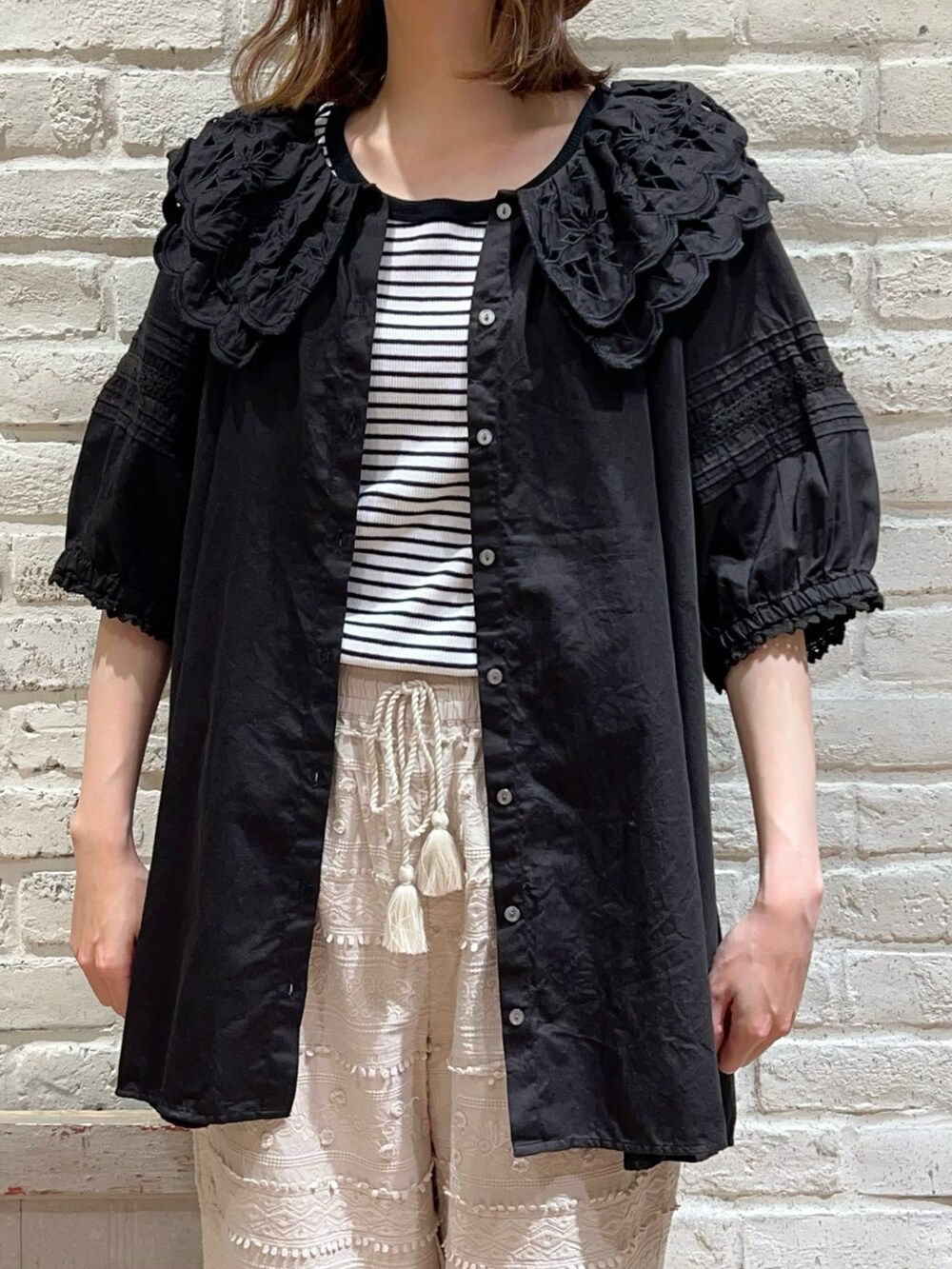 ホワイト系のTシャツ/カットソー、ブラック系のチュニック、ブラック系のハンドバッグを着用したレディースの春コーディネートの2枚目の写真
