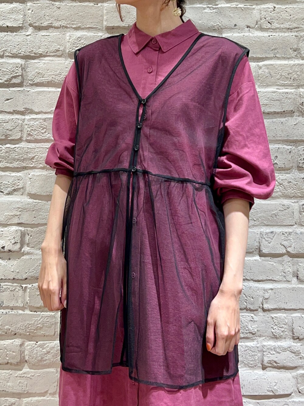 パープル系のワンピース、ブラック系のベスト、ブルー系のデニムパンツを着用したレディースの秋コーディネートの2枚目の写真