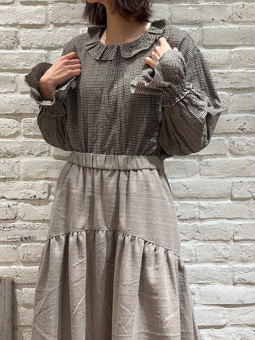 ブラウン系のシャツ/ブラウス、ホワイト系のベスト、ブラウン系のスカートを着用したレディースの冬コーディネートの3枚目の写真