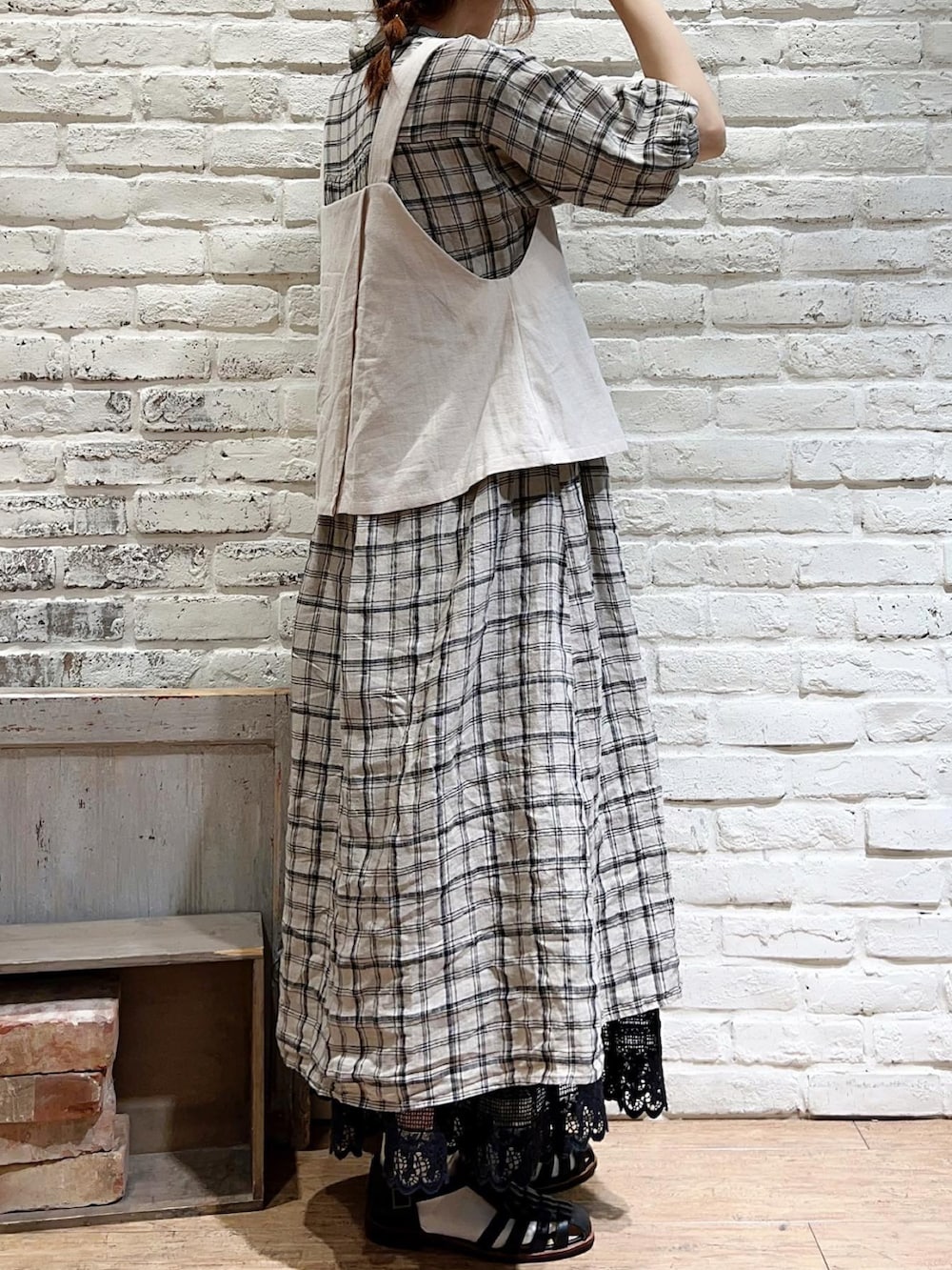 ベージュ系のベスト、ホワイト系のワンピース、ブラック系のスカートを着用したレディースの夏コーディネートの3枚目の写真