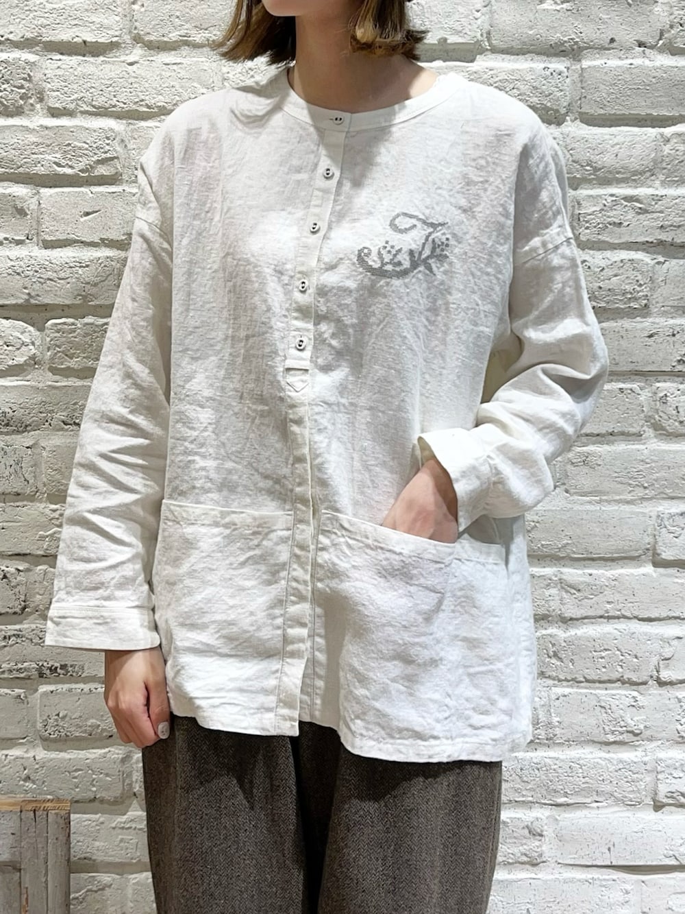 グリーン系のノーカラーコート、ホワイト系のシャツ/ブラウス、ブラウン系のその他パンツを着用したレディースの冬コーディネートの3枚目の写真