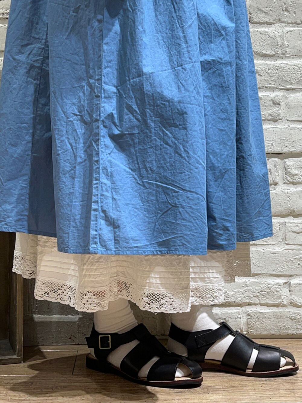 ブルー系のワンピース、ホワイト系のスカート、ブラック系のサンダルを着用したレディースの春コーディネートの5枚目の写真