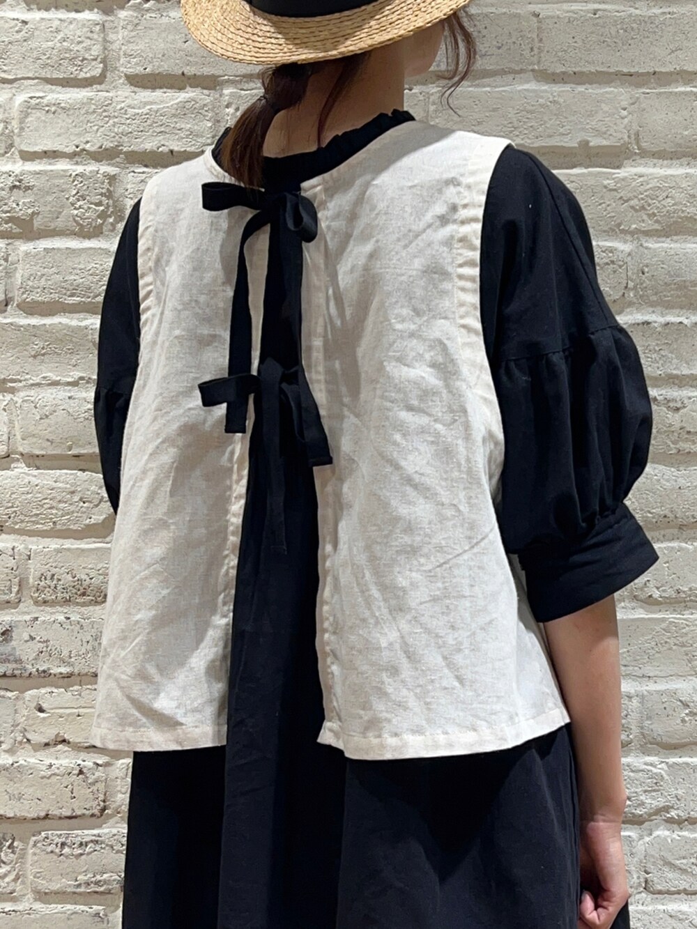 ホワイト系のベスト、ブラック系のチュニック、ブラウン系のその他パンツを着用したレディースの夏コーディネートの2枚目の写真