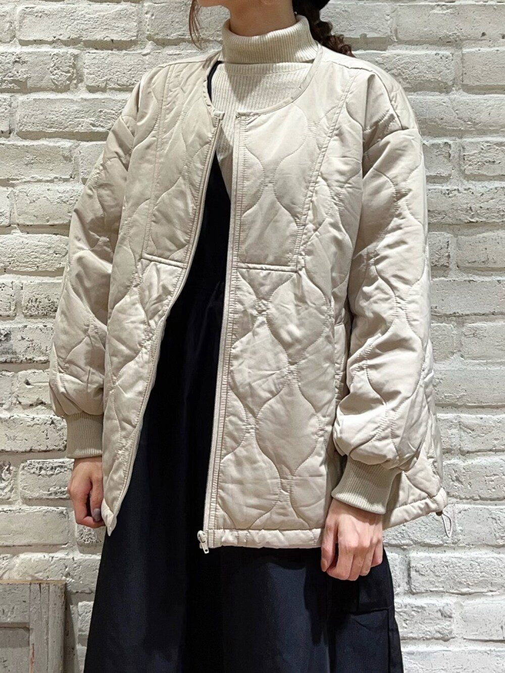 ベージュ系のブルゾン、ブラック系のワンピース、ブラック系のブーツを着用したレディースの冬コーディネートの2枚目の写真