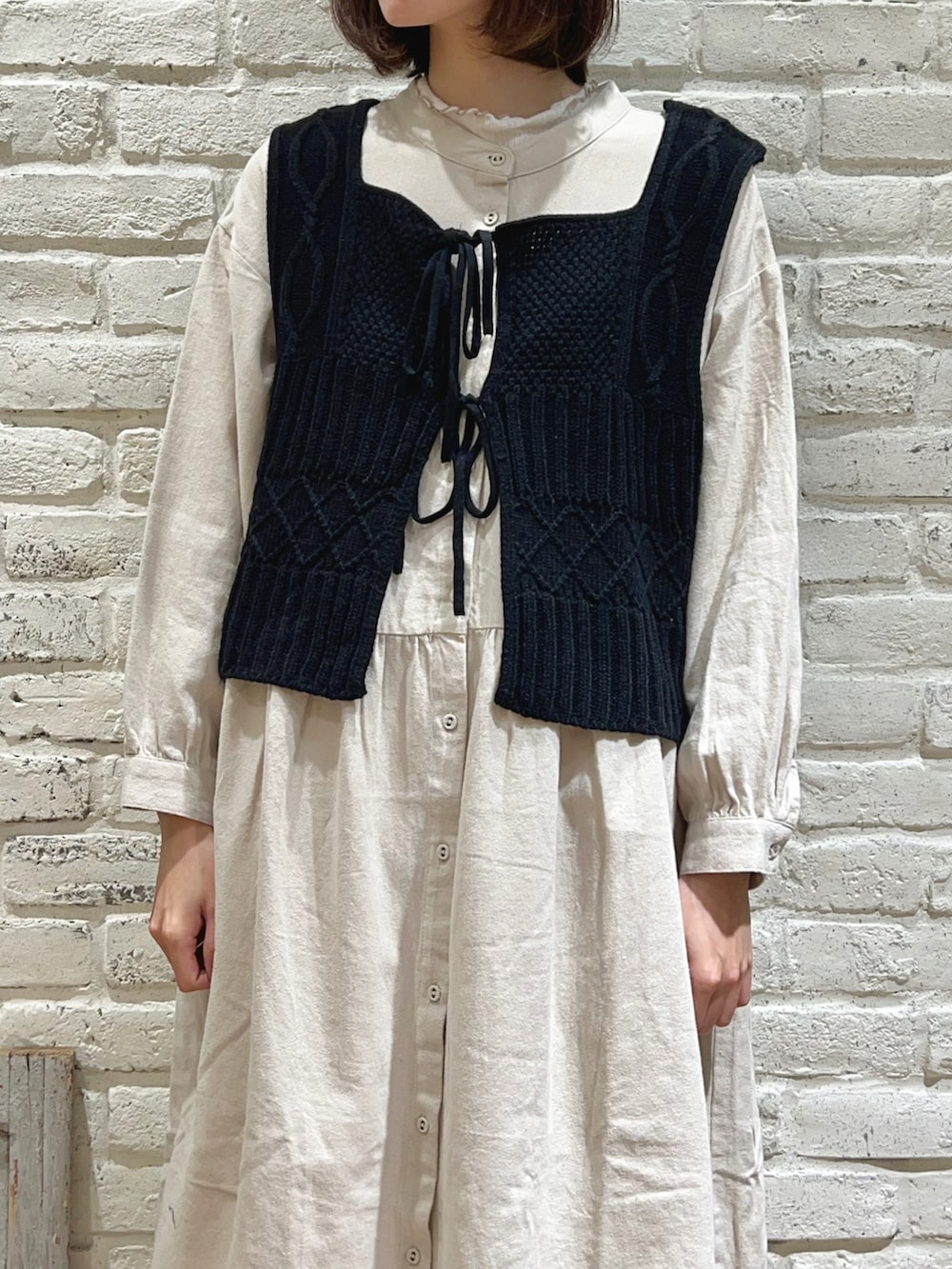 ホワイト系のTシャツ/カットソー、ブラック系のベスト、ホワイト系のワンピースを着用したレディースの冬コーディネートの3枚目の写真