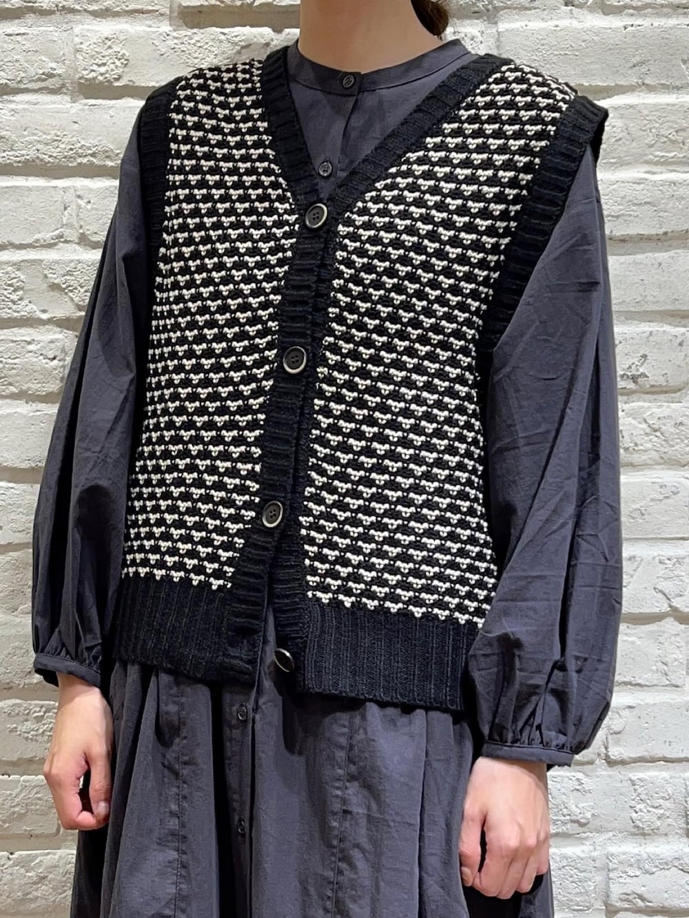 ブラック系のベスト、グレー系のワンピース、ベージュ系のその他パンツを着用したレディースの秋コーディネートの2枚目の写真