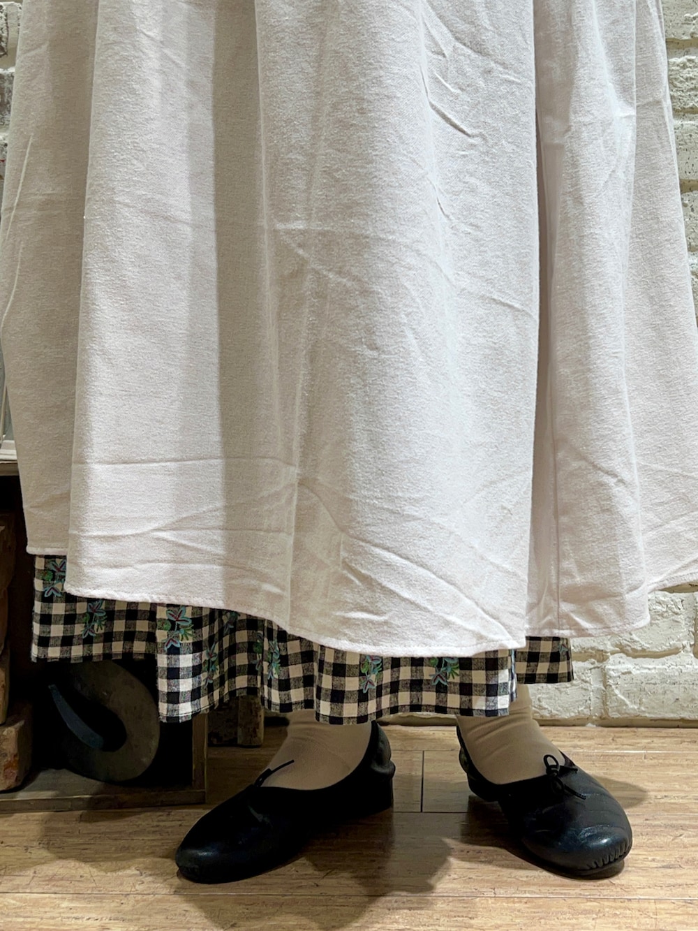 ブラック系のニット/セーター、ホワイト系のワンピース、ベージュ系のスカートを着用したレディースの冬コーディネートの5枚目の写真