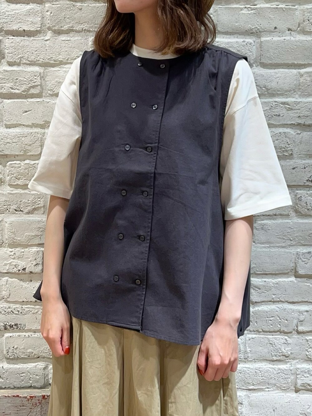 グレー系のベスト、ホワイト系のTシャツ/カットソー、グレー系のハンドバッグを着用したレディースの夏コーディネートの2枚目の写真