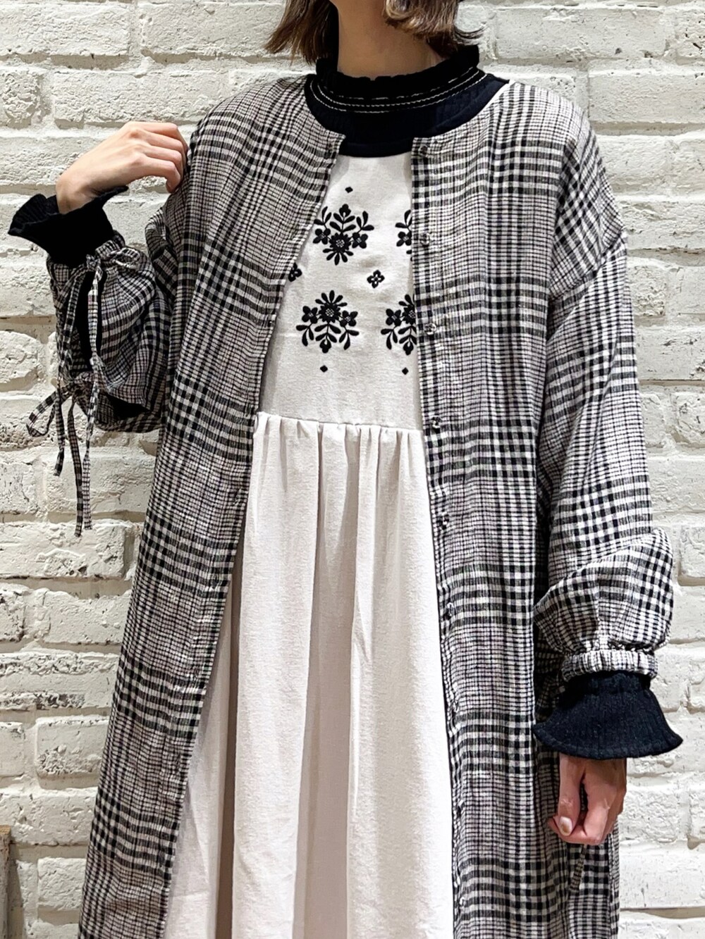 ブラック系のニット/セーター、ホワイト系のワンピース、ホワイト系のワンピースを着用したレディースの冬コーディネートの2枚目の写真