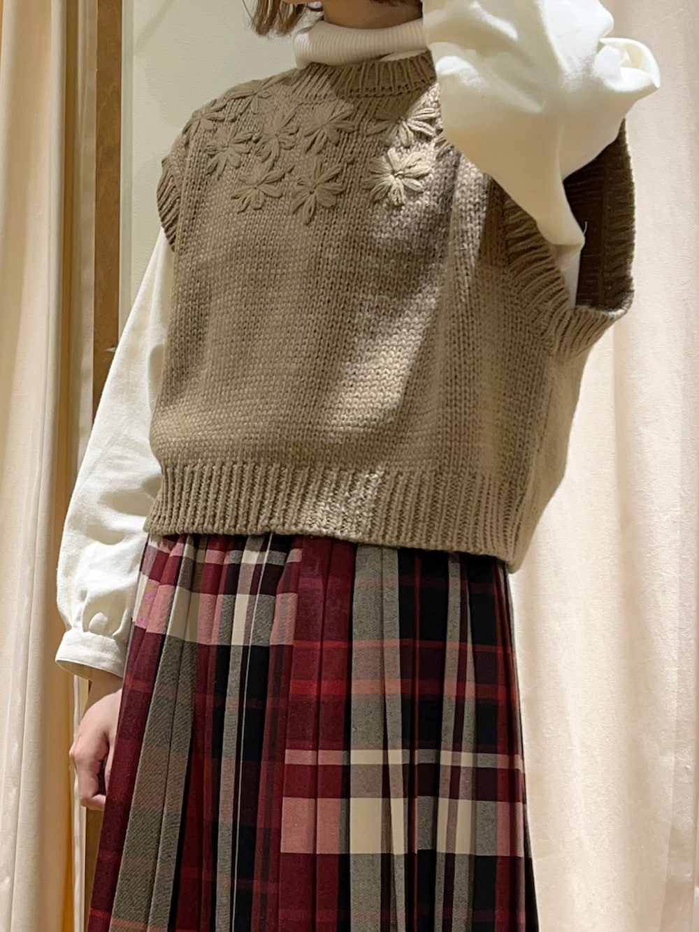 ホワイト系のニット/セーター、ブラウン系のベスト、ホワイト系のチュニックを着用したレディースの冬コーディネートの2枚目の写真