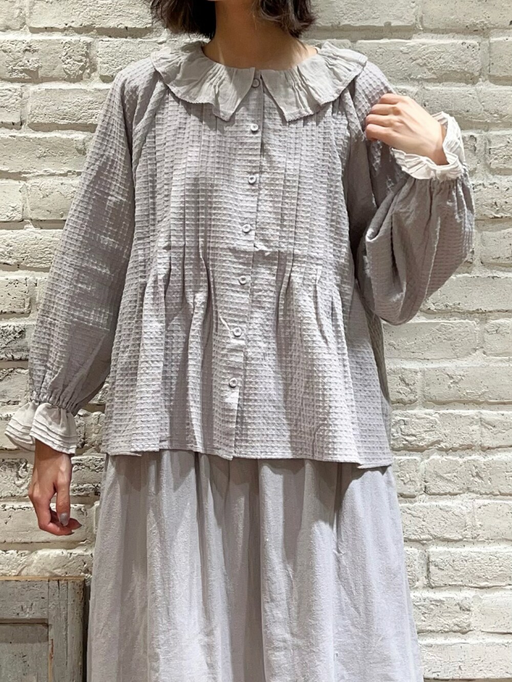 ホワイト系のノーカラージャケット、グレー系のシャツ/ブラウス、ブルー系のスカートを着用したレディースの冬コーディネートの3枚目の写真