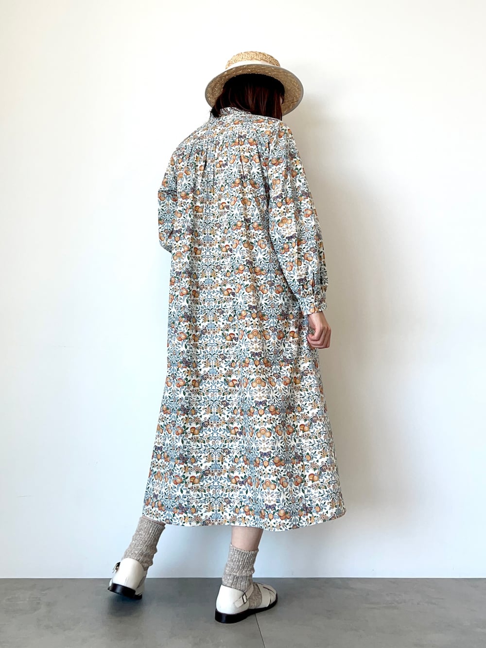 オレンジ系のワンピース、ホワイト系のサンダル、ホワイト系のハットを着用したレディースの春コーディネートの4枚目の写真