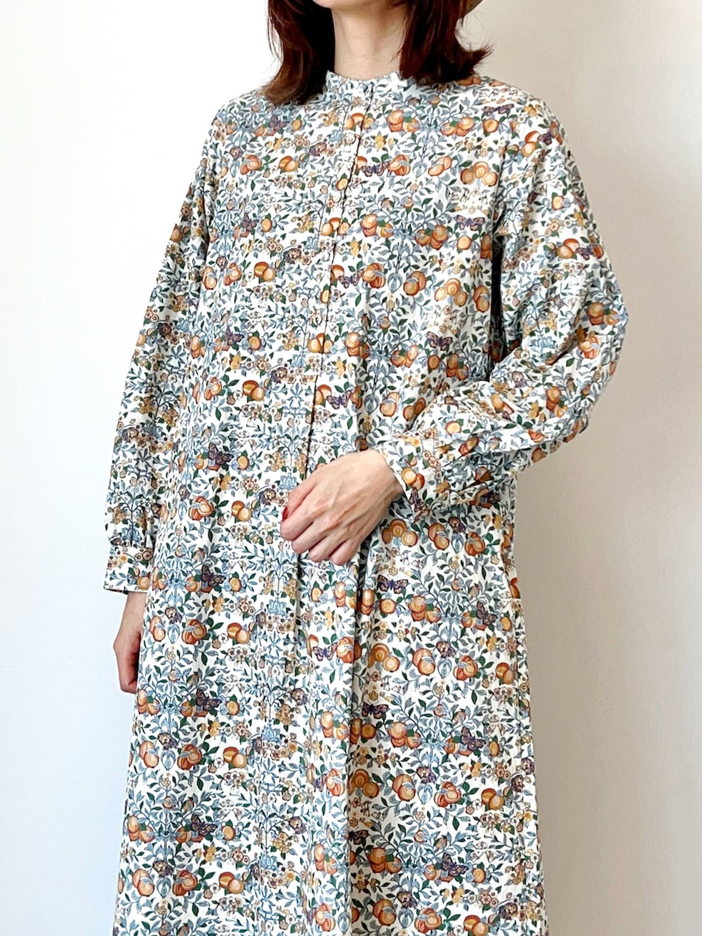 オレンジ系のワンピース、ホワイト系のサンダル、ホワイト系のハットを着用したレディースの春コーディネートの2枚目の写真