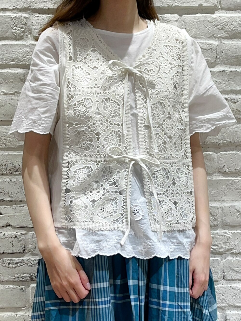 ホワイト系のシャツ/ブラウス、ホワイト系のベスト、グリーン系のスカートを着用したレディースの夏コーディネートの2枚目の写真