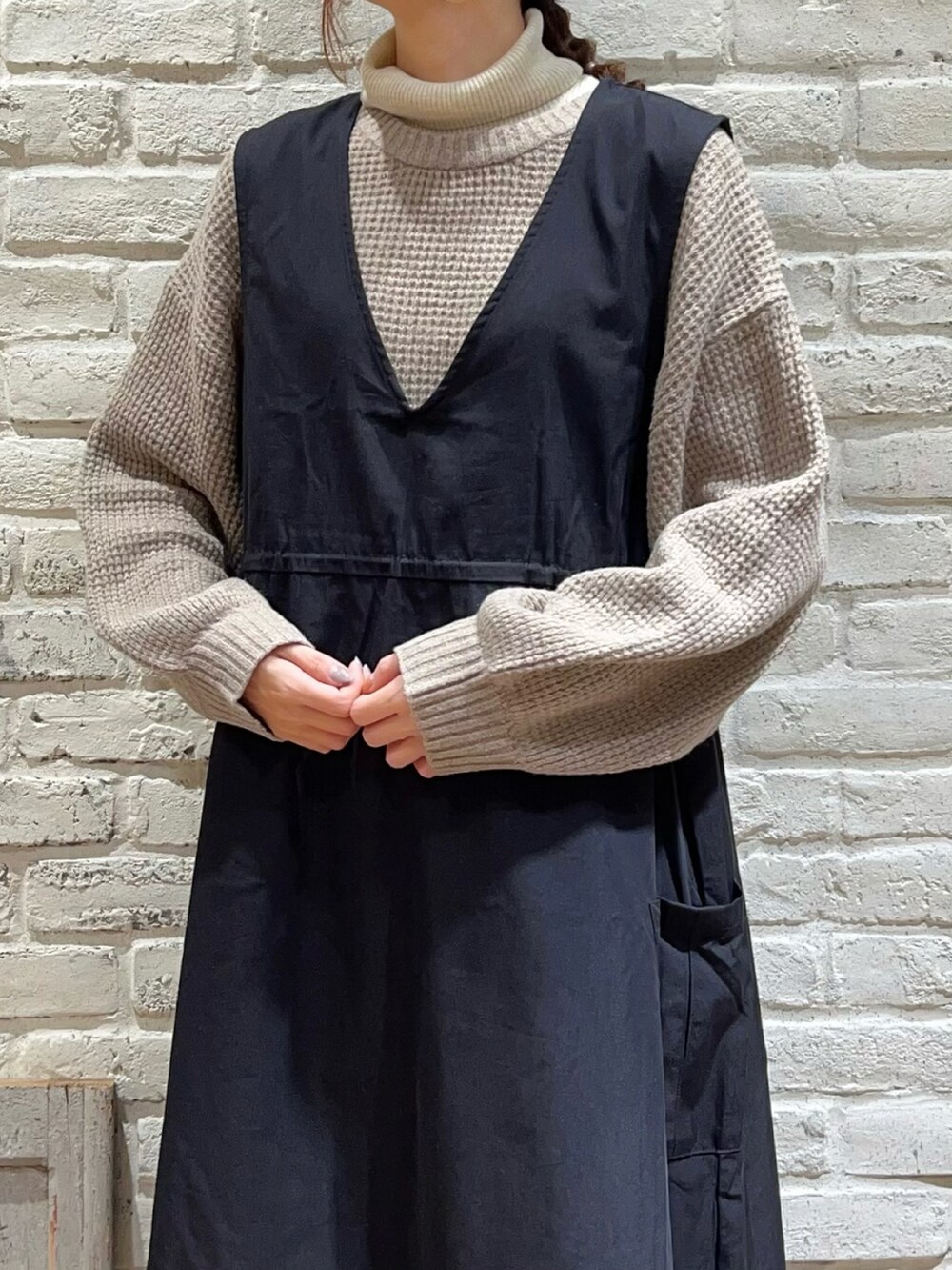 ホワイト系のニット/セーター、ブラック系のワンピース、ブラック系のブーツを着用したレディースの冬コーディネートの2枚目の写真