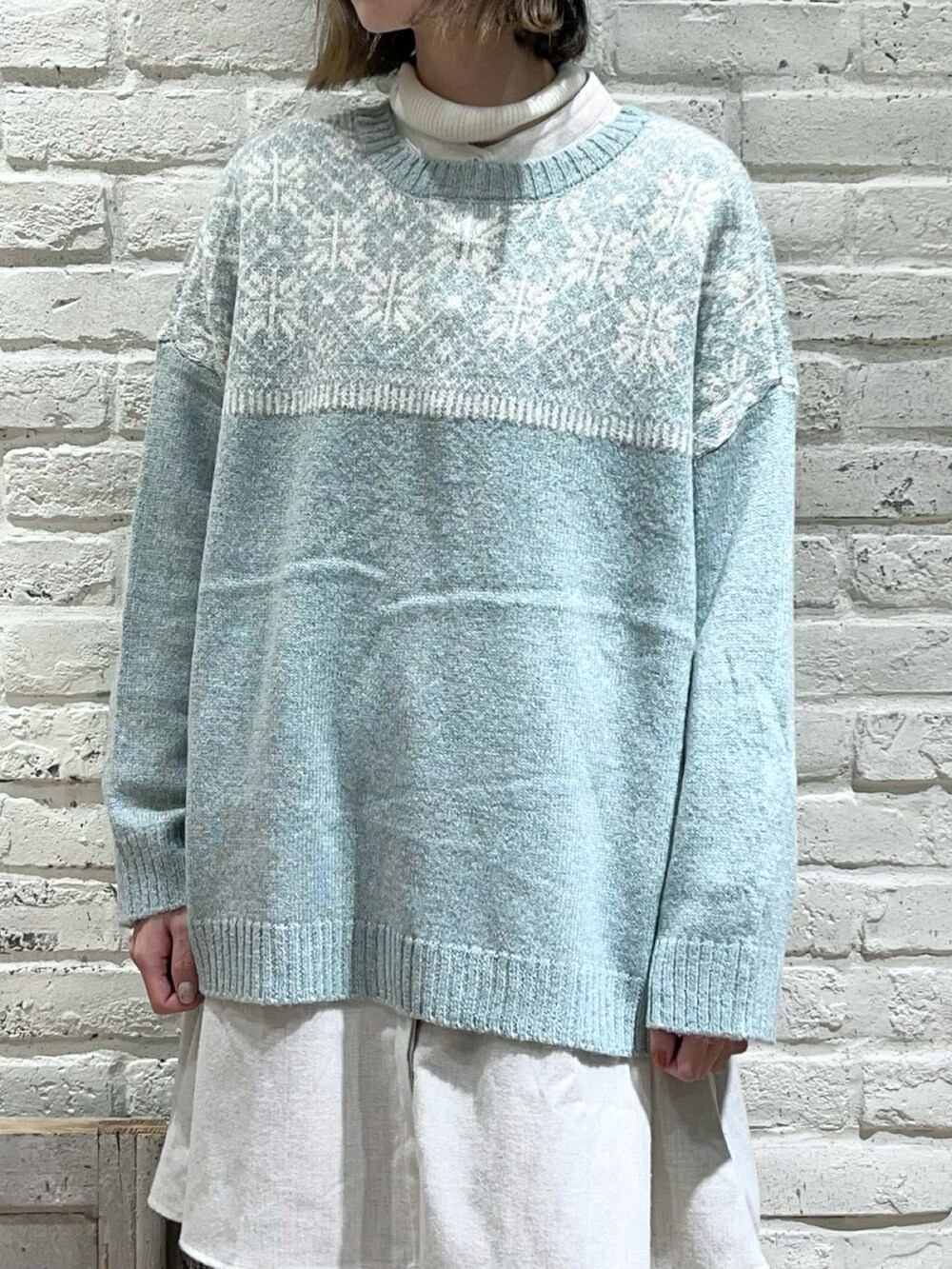 ホワイト系のニット/セーター、グリーン系のカーディガン/ボレロ、グレー系のチュニックを着用したレディースの冬コーディネートの2枚目の写真