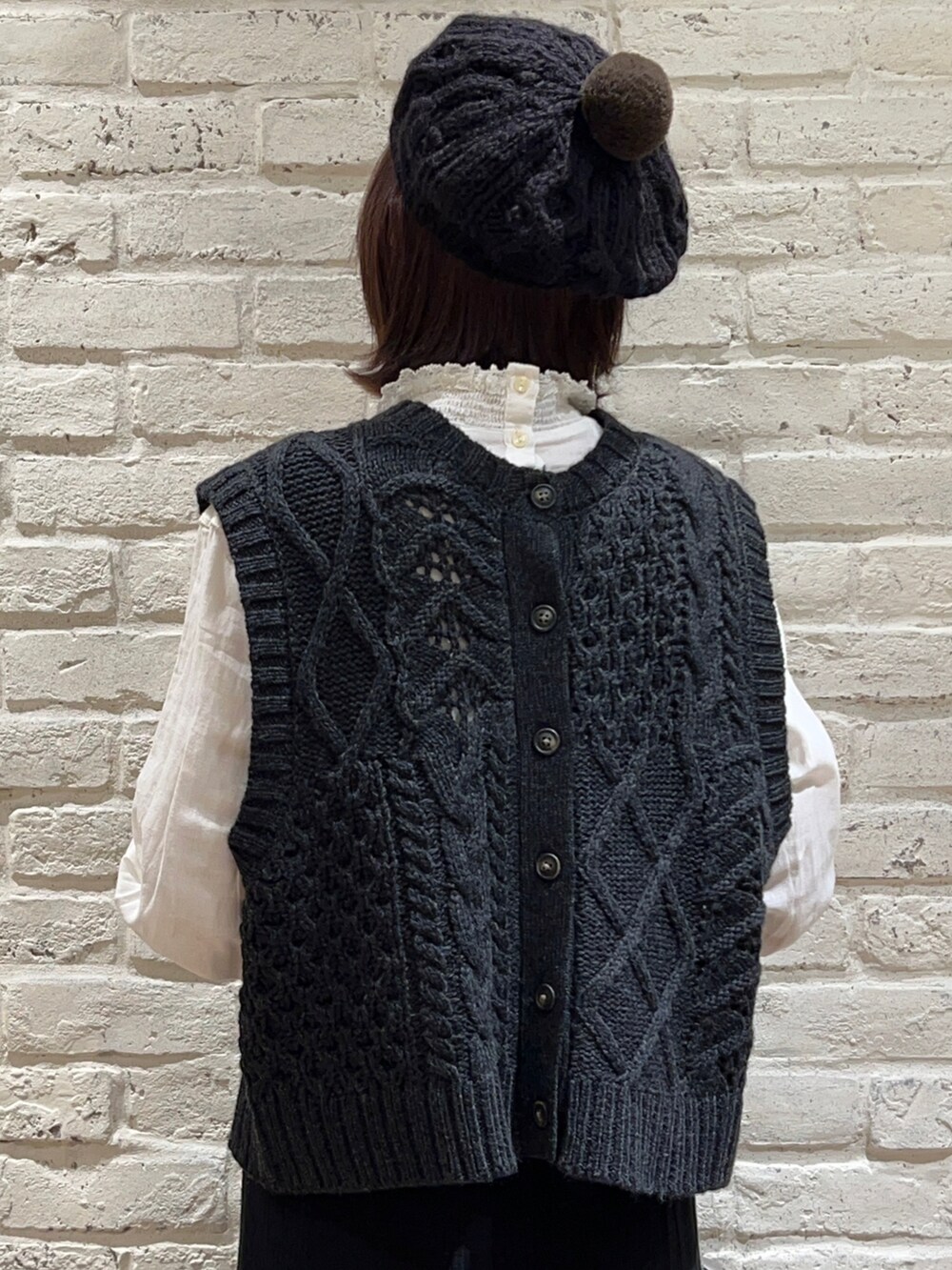 グレー系のベスト、ホワイト系のシャツ/ブラウス、ブラック系のスカートを着用したレディースの冬コーディネートの5枚目の写真