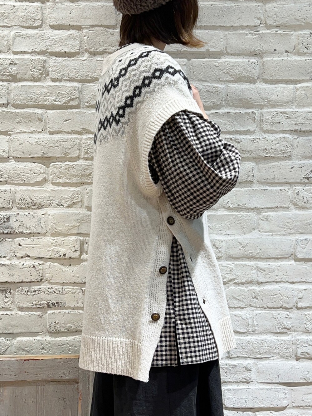 ホワイト系のベスト、ブラック系のチュニック、ブラック系のスカートを着用したレディースの冬コーディネートの4枚目の写真