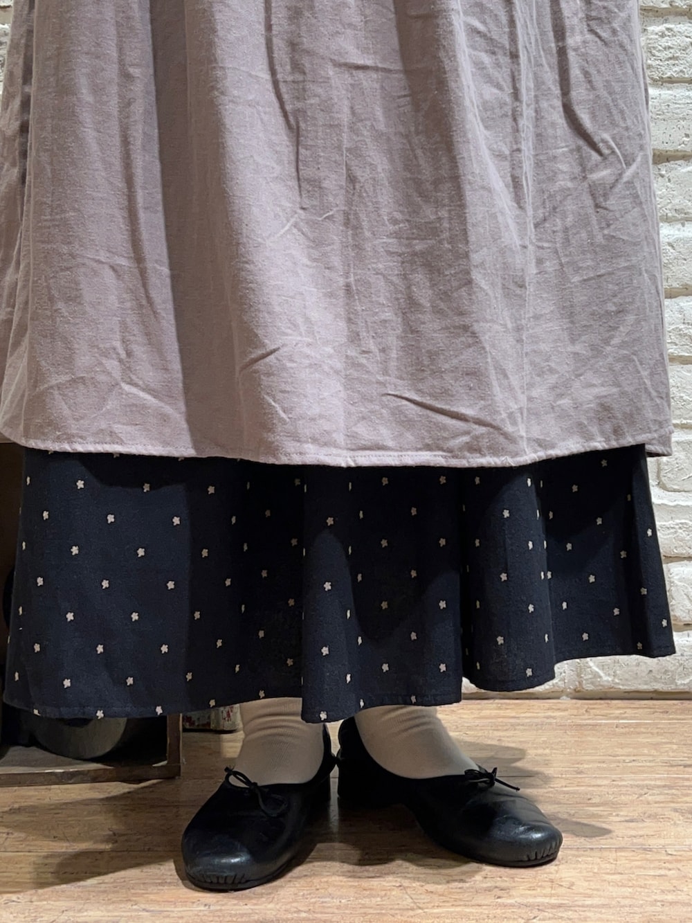 ブラック系のTシャツ/カットソー、ベージュ系のワンピース、ブラック系のスカートを着用したレディースの秋コーディネートの5枚目の写真