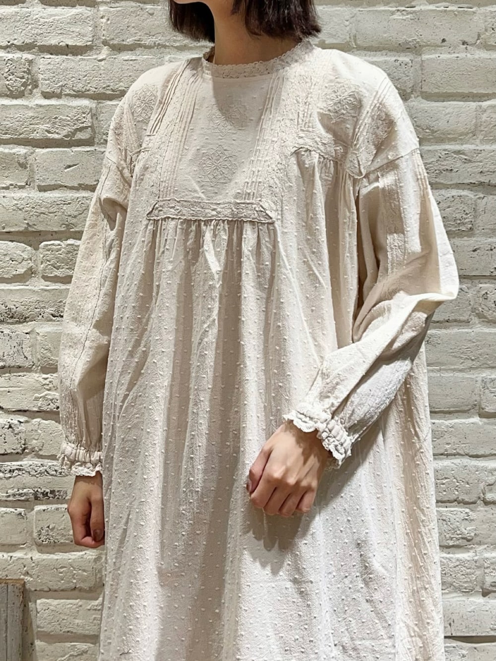 ベージュ系のカーディガン/ボレロ、ホワイト系のワンピース、ブラウン系のハンドバッグを着用したレディースの冬コーディネートの3枚目の写真