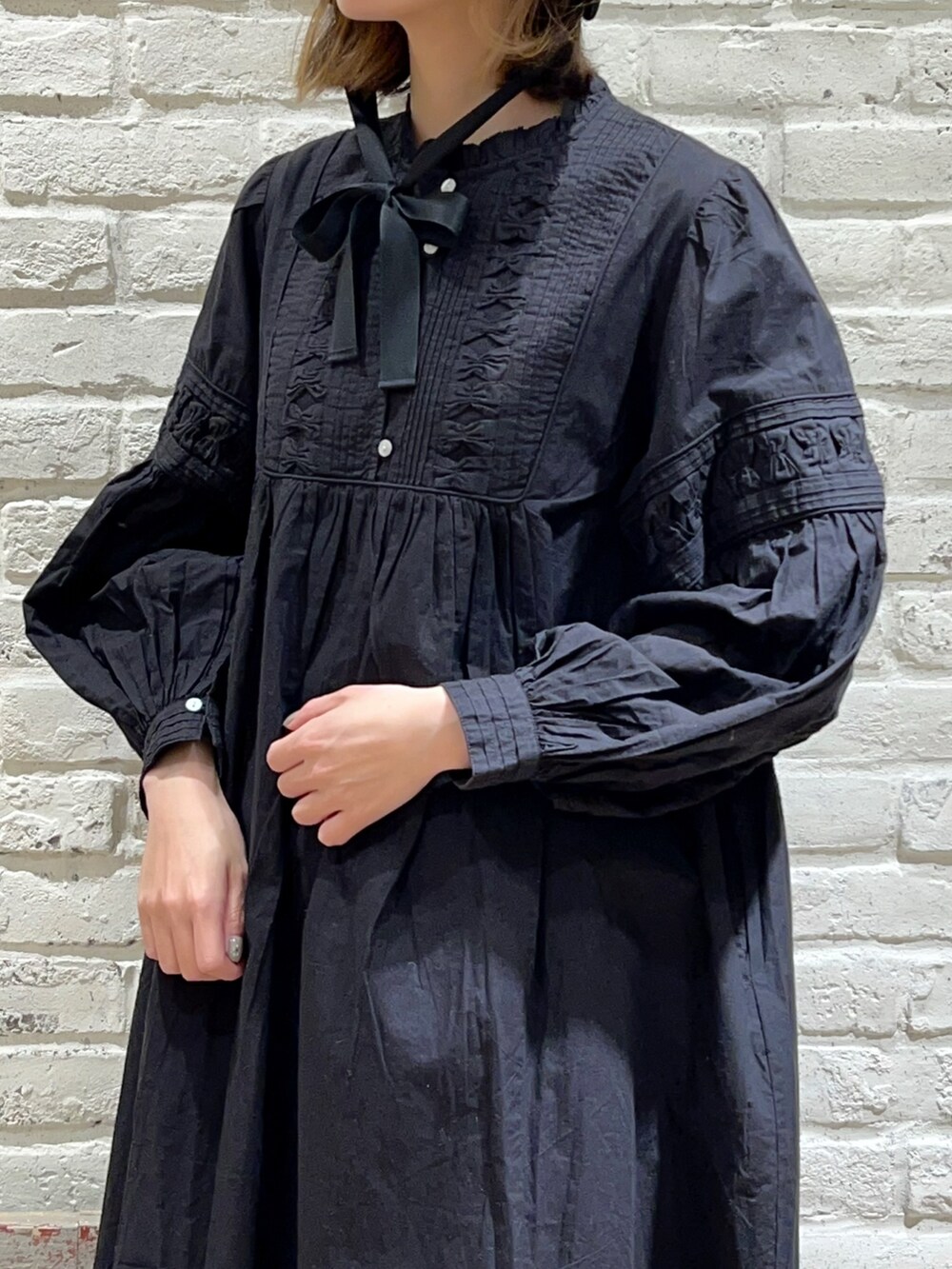 ホワイト系のカーディガン/ボレロ、ブラック系のワンピース、パープル系のスカートを着用したレディースの冬コーディネートの2枚目の写真