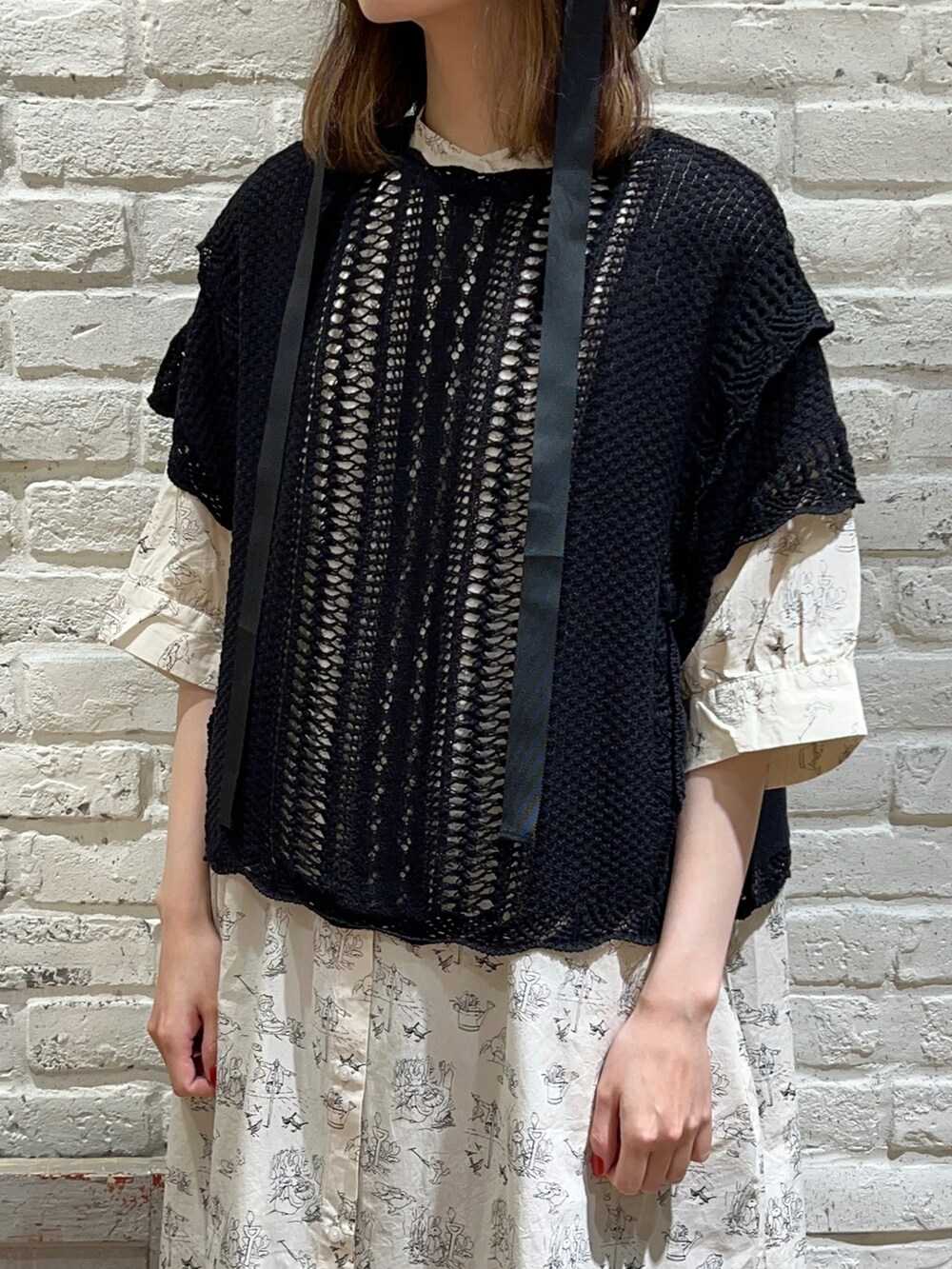 ブラック系のベスト、ブラック系のハンドバッグ、ホワイト系のワンピースを着用したレディースの夏コーディネートの2枚目の写真