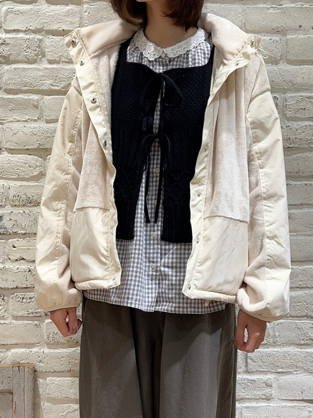 グレー系のシャツ/ブラウス、ブラック系のベスト、ホワイト系のノーカラージャケットを着用したレディースの冬コーディネートの2枚目の写真